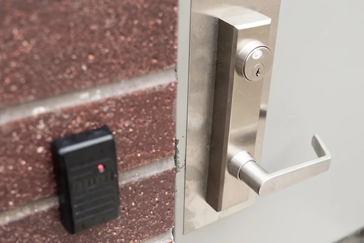 Commercial door with stainless steel keyed lever lock and access control card reader on a brick wall, Washington DC commercial locksmith