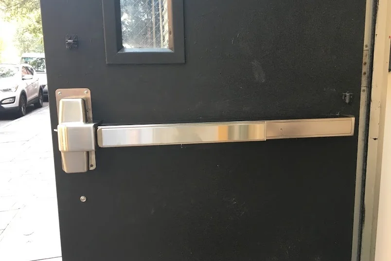 Stainless steel panic bar exit device installed on a black commercial door, Washington DC panic bar repair