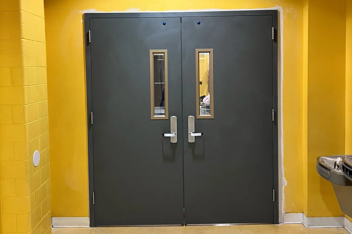 Newly installed gray steel double doors with vision windows and lever handles in a Washington DC commercial building, door replacement