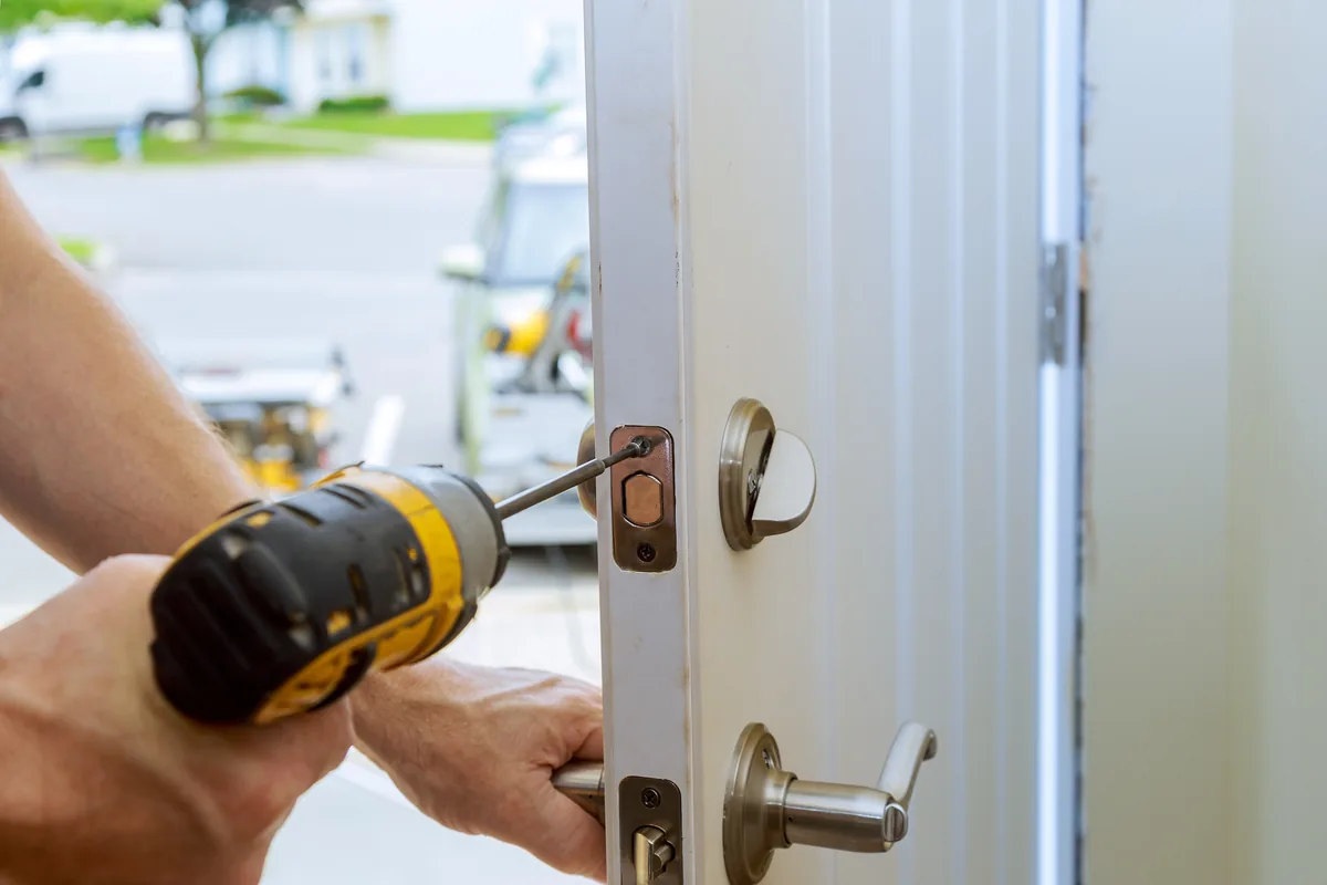 Locksmith using a power drill to install a deadbolt and lever handle on a home front door, Washington DC residential locksmith